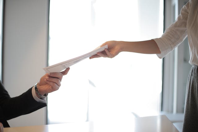 a hand handing a document to another hand